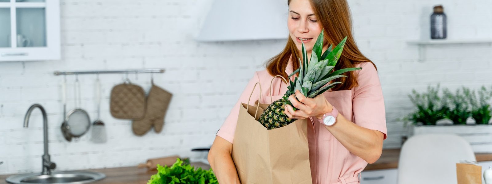 woman with the grocery store packet in the hands. Kitchen background. Young woman with healthy food.
