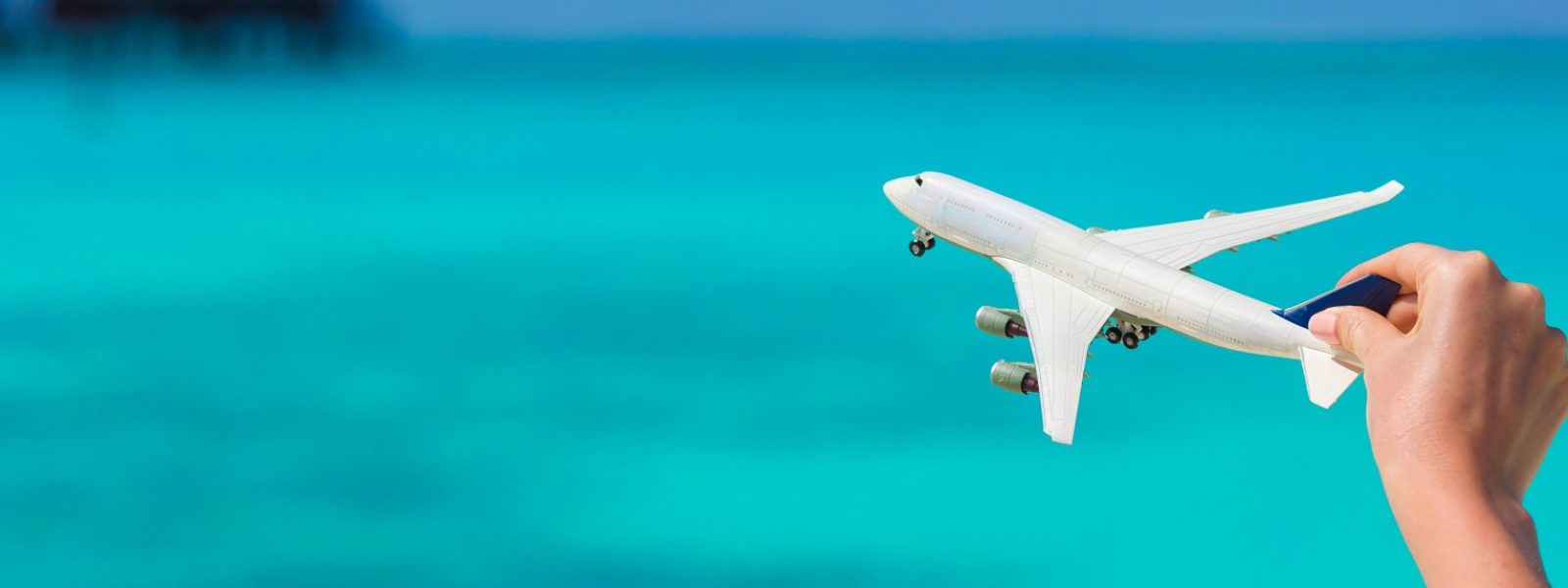 Small white miniature of an airplane on background of turquoise sea